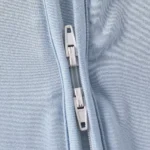 Close-up of baby romper two-way zipper system, featuring dual high-quality sliders for flexible top or bottom access. Premium functional infant jumpsuit hardware from a professional clothing manufacturer.