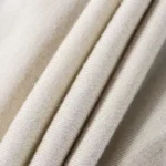 Close-up of premium baby romper fabric, featuring ultra-soft breathable cotton jersey, high-density fine knit texture, and eco-friendly neutral dyeing. Professional infant apparel textile from an expert clothing manufacturer.