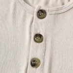 Close-up of baby romper Henley neckline, featuring three decorative wood-look buttons, precision-stitched placket, and premium soft rib-knit cotton fabric. High-quality infant apparel detailing from a professional clothing manufacturer.
