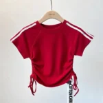Custom girls' red cropped T-shirt with side drawstrings and shoulder stripes, trendy fitted baby tee, short sleeve kids' activewear, professional OEM/ODM apparel manufacturer.