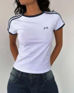 Custom white womens ringer T-shirt with navy blue contrast trim, stylish striped shoulder details and delicate chest embroidery, premium slim fit cropped tee from a professional OEM/ODM garment manufacturer.